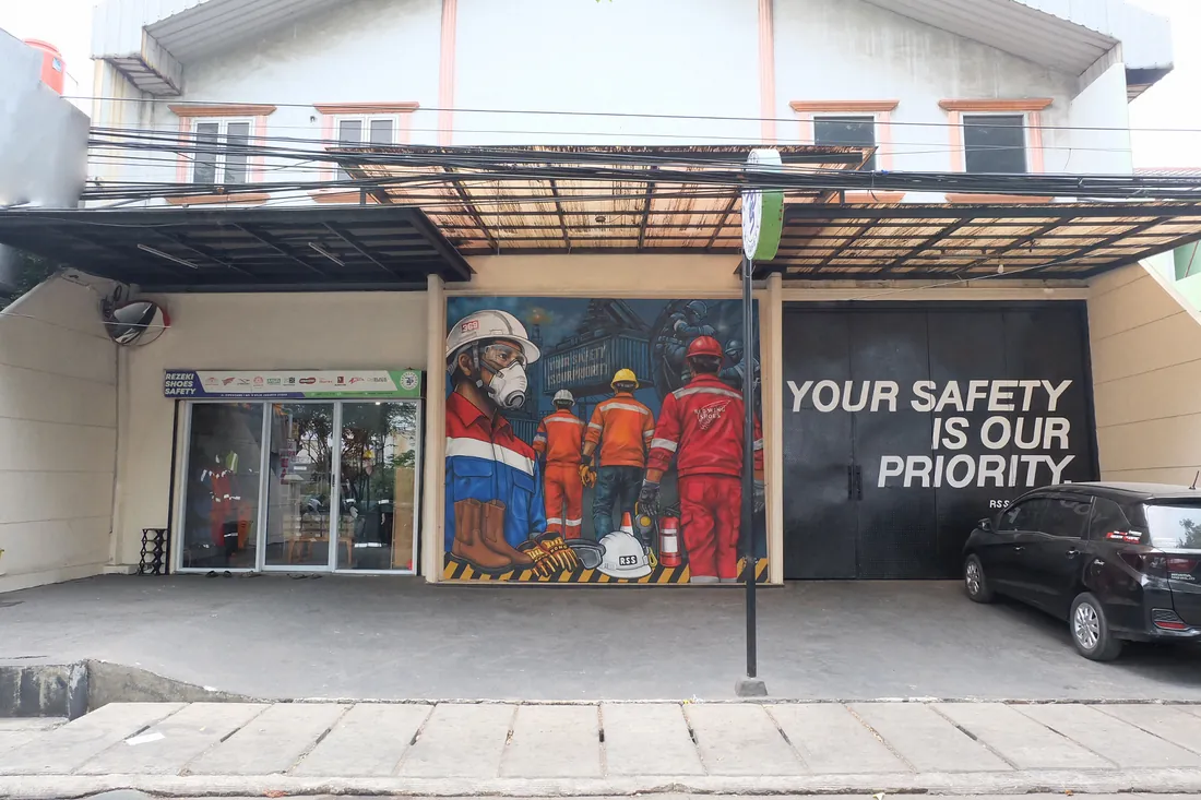 Tampak depan toko Rezeki Shoes Safety di Jl. Cipeucang, Jakarta Utara, dengan mural keselamatan kerja